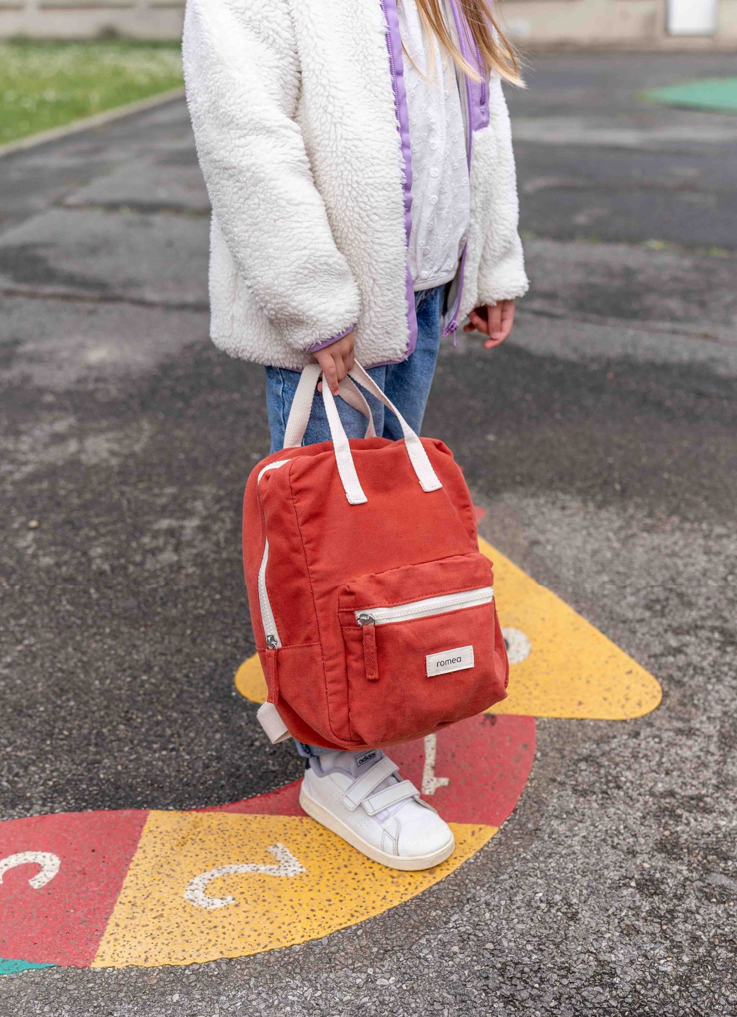 sac à dos rouge brique tenue à la main