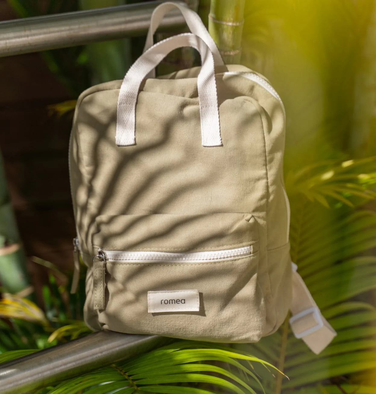 sac à dos de couleur vert posé à coté d'un palmier