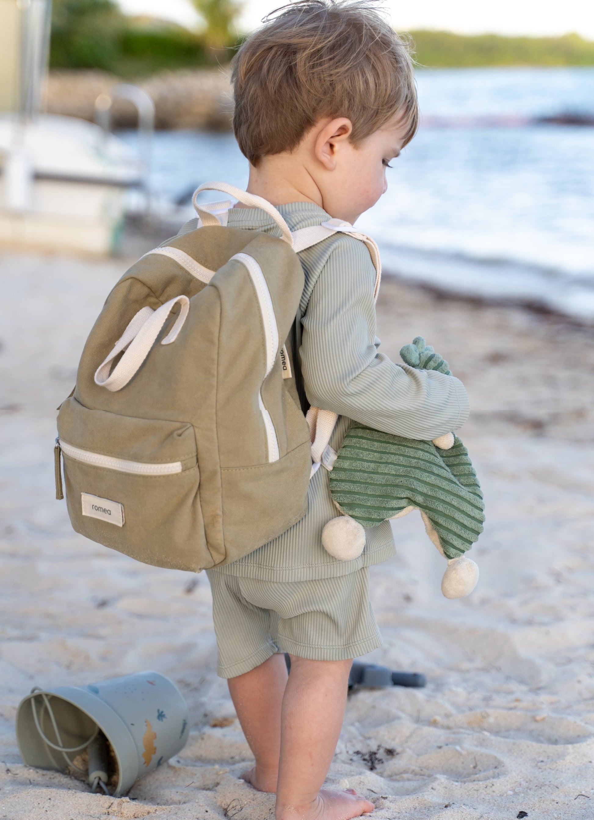 sac à dos de couleur vert porté sur une plage de dos