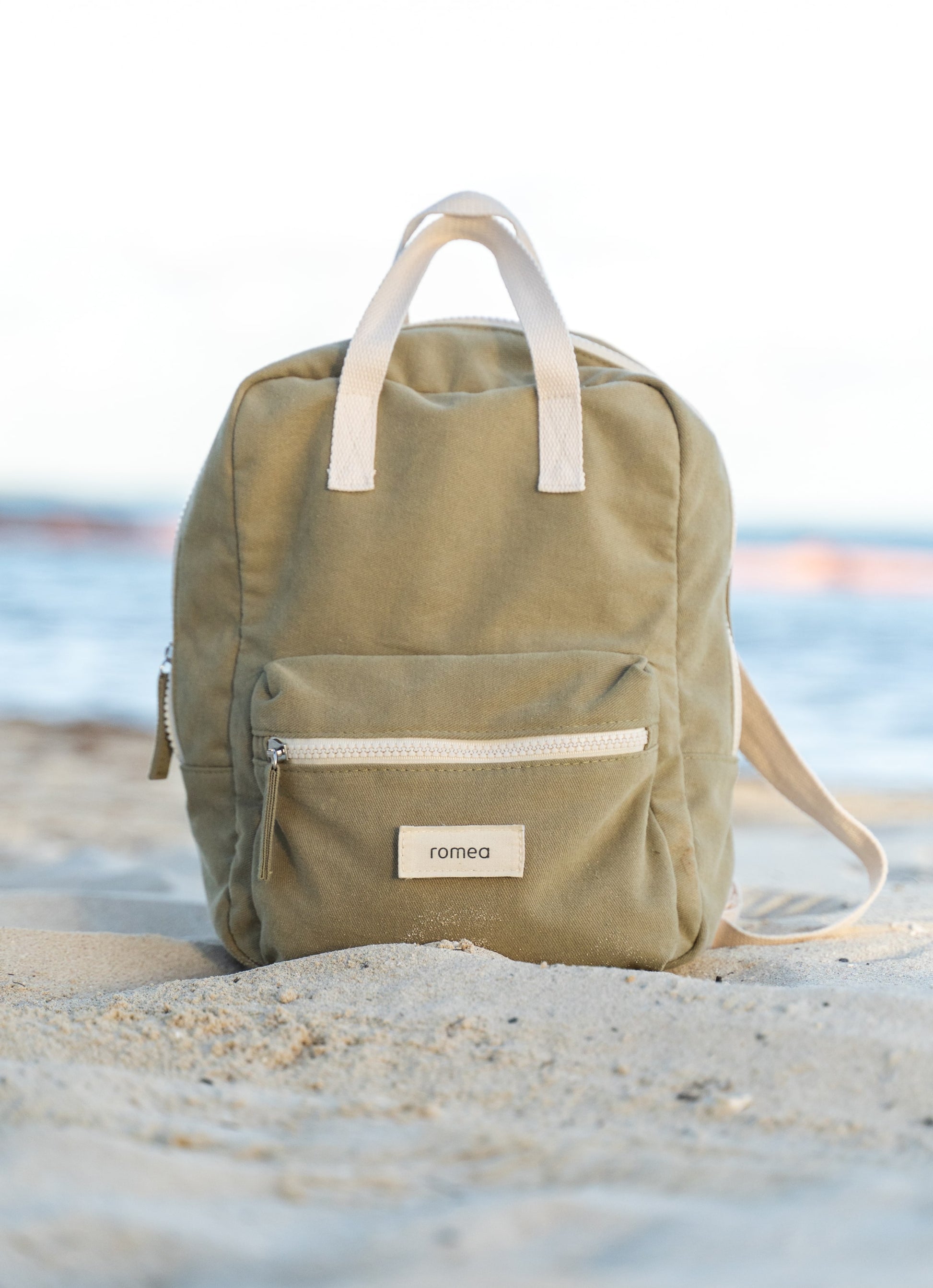 sac à dos vert posé sur du sable