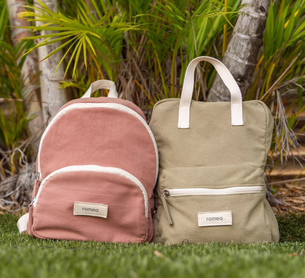 sac de couleur rose et vert kaki posé dans l'herbe