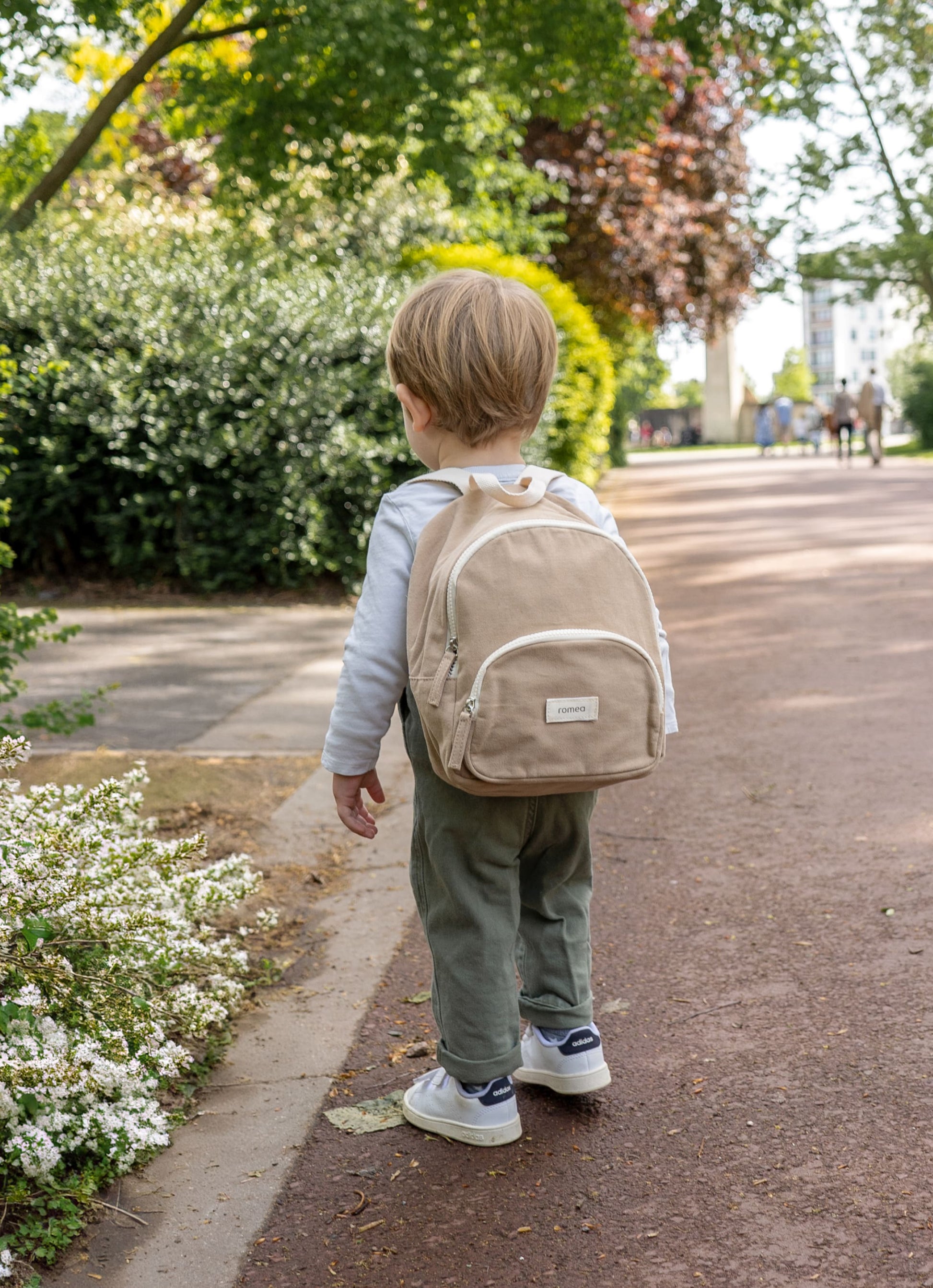 sac à dos de couleur beige porté de dos par un garçon