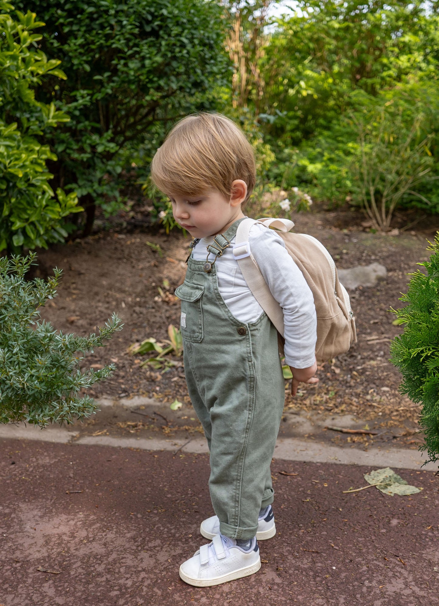 petit garçon portant un sac à dos de couleur beige de face