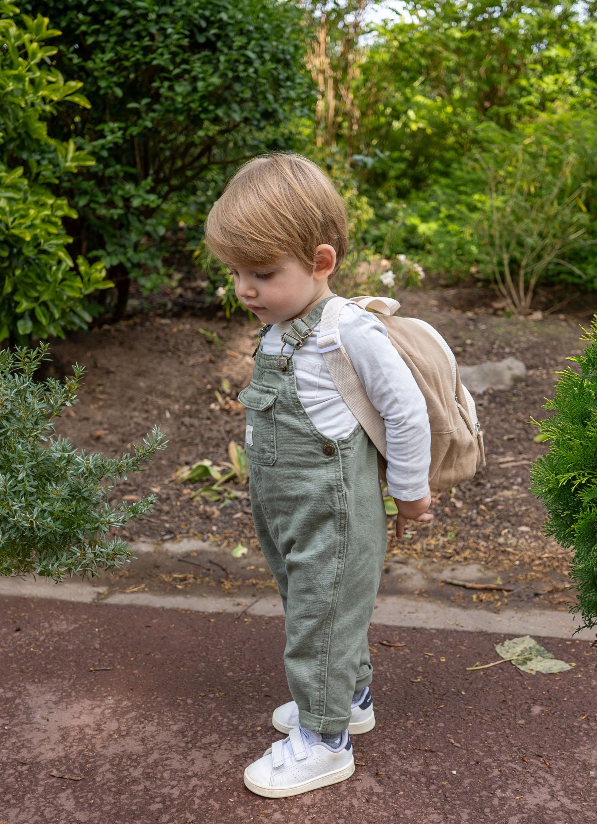 petit garçon portant un sac à dos de couleur beige de face