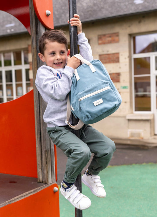 petit garçon descend sur une barre avec un sac à dos romea bleu