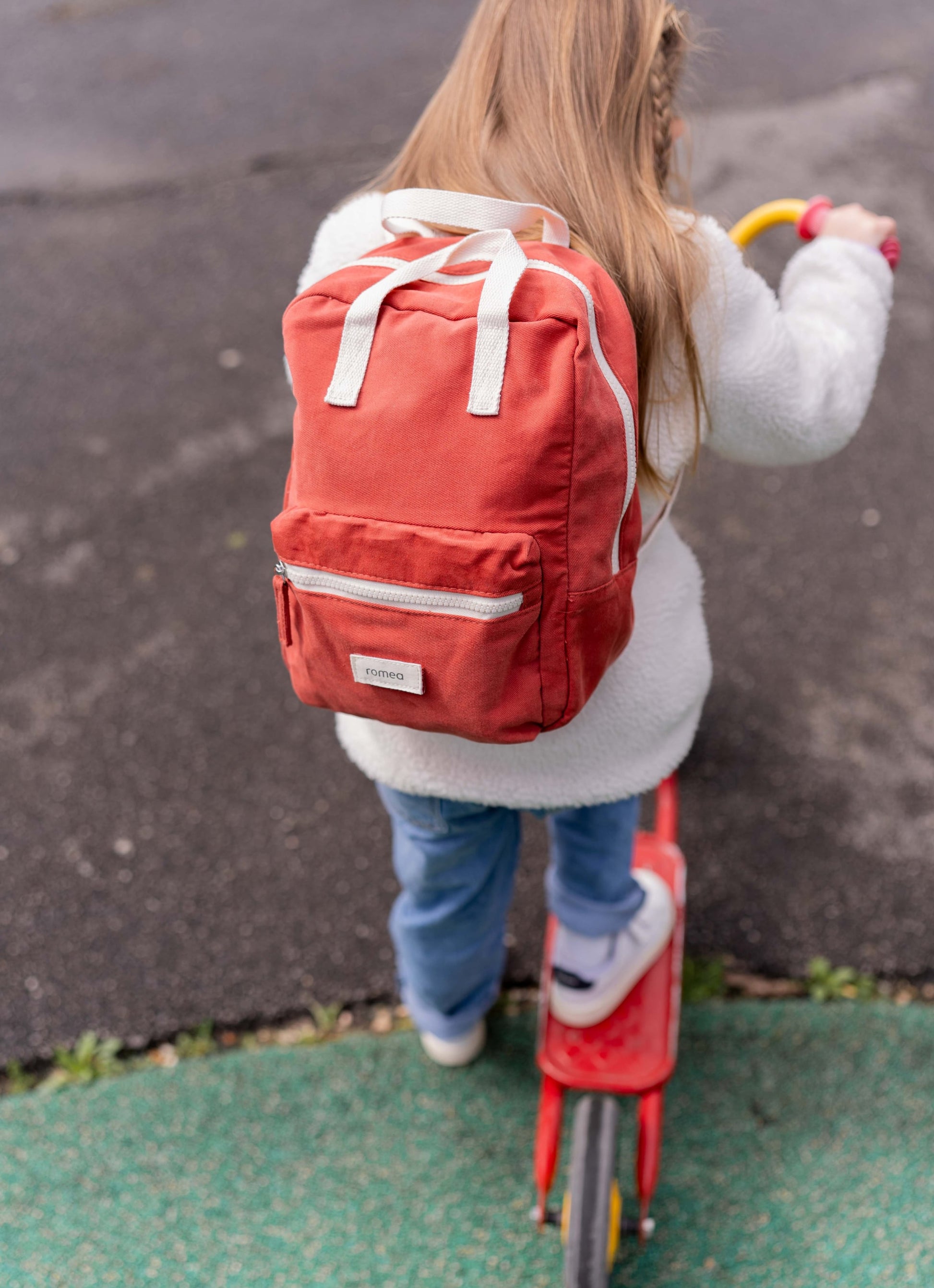 une fille portant un sac rouge brique de dos 