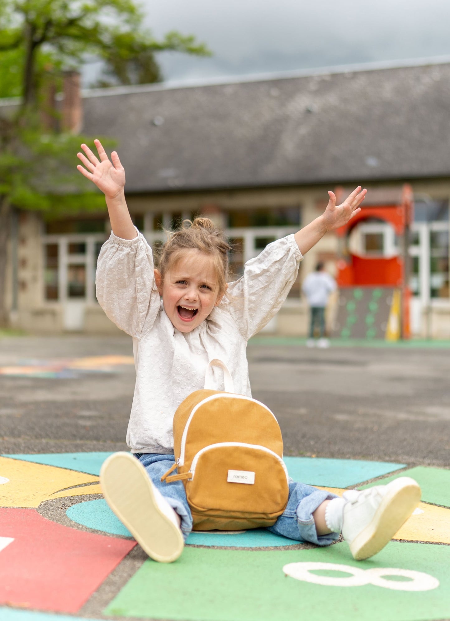 petite fille assise avec un sac à dos romea moutarde 